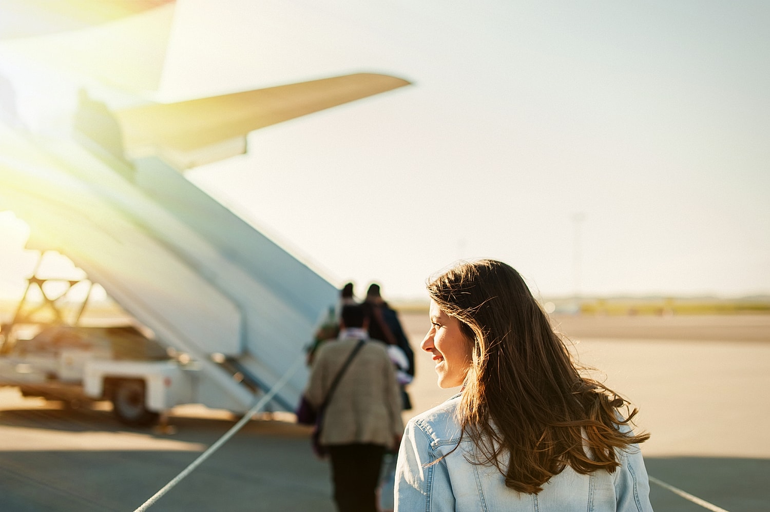 Woman boarding a plane on sunny day.