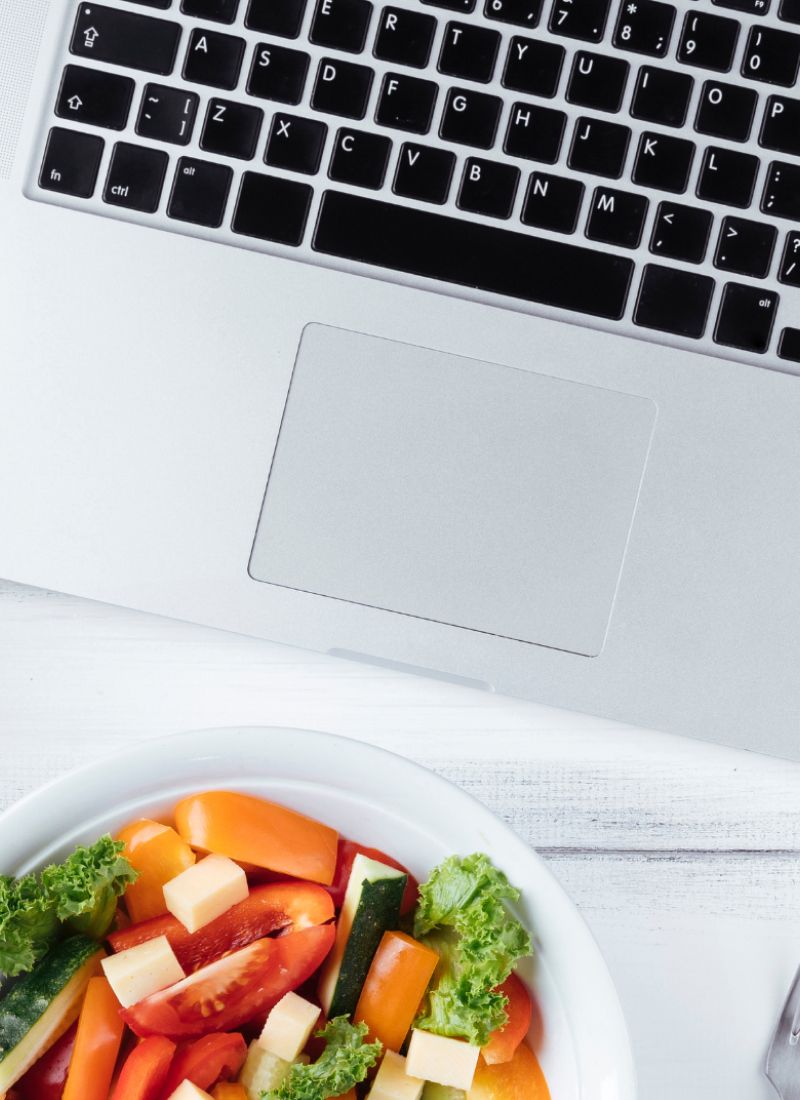 Fresh salad beside a laptop on a table.