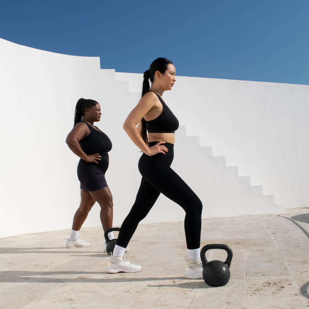 Women exercising outdoors with kettlebells.