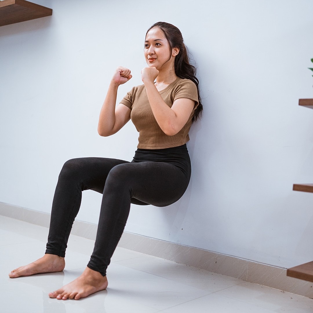 Woman stretching on yoga mat indoors.