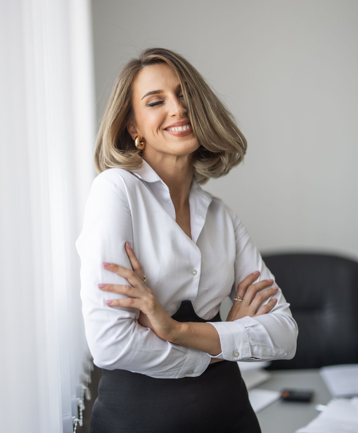 Smiling woman in professional attire, arms crossed.