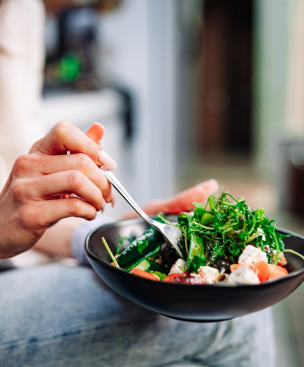 Person eating a fresh salad with vegetables.
