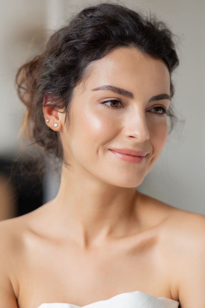Smiling woman with natural makeup and elegant hairstyle.