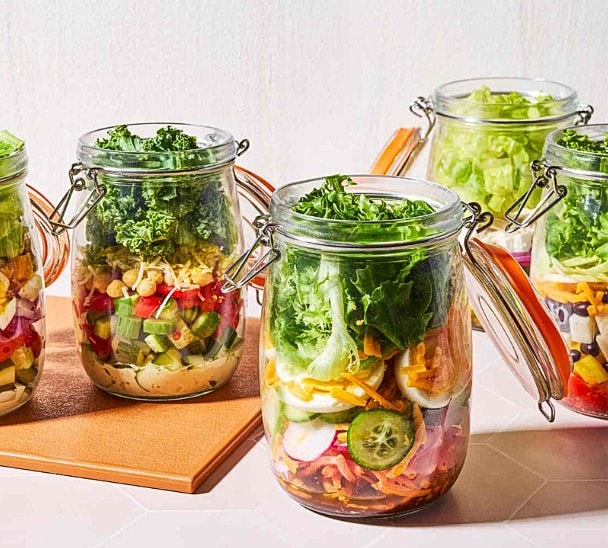 Colorful salad jars stacked on a countertop.
