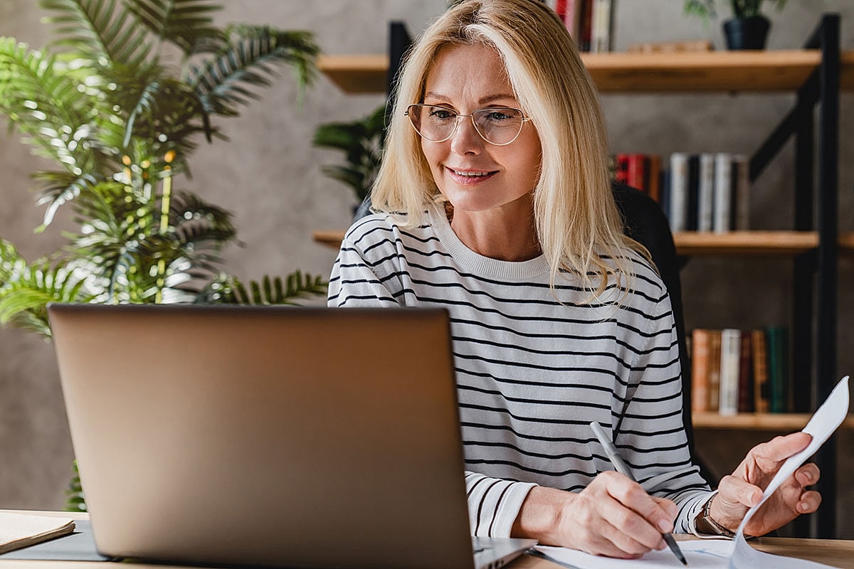 Smiling woman using a laptop at home.