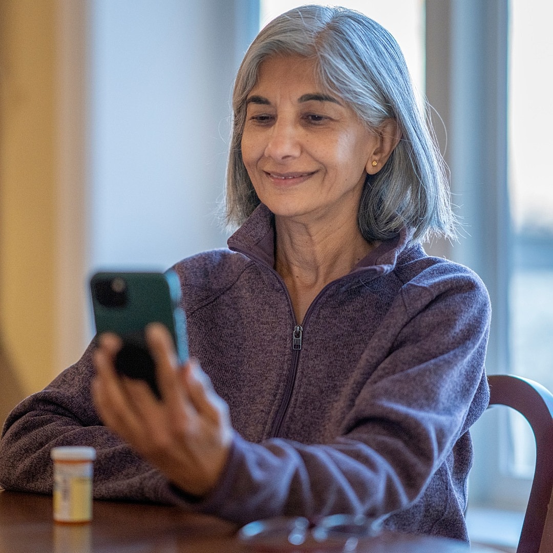 Woman smiling while using smartphone indoors.