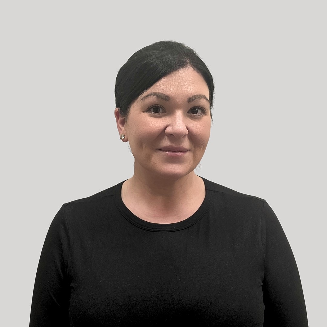 Woman smiling against a gray background.