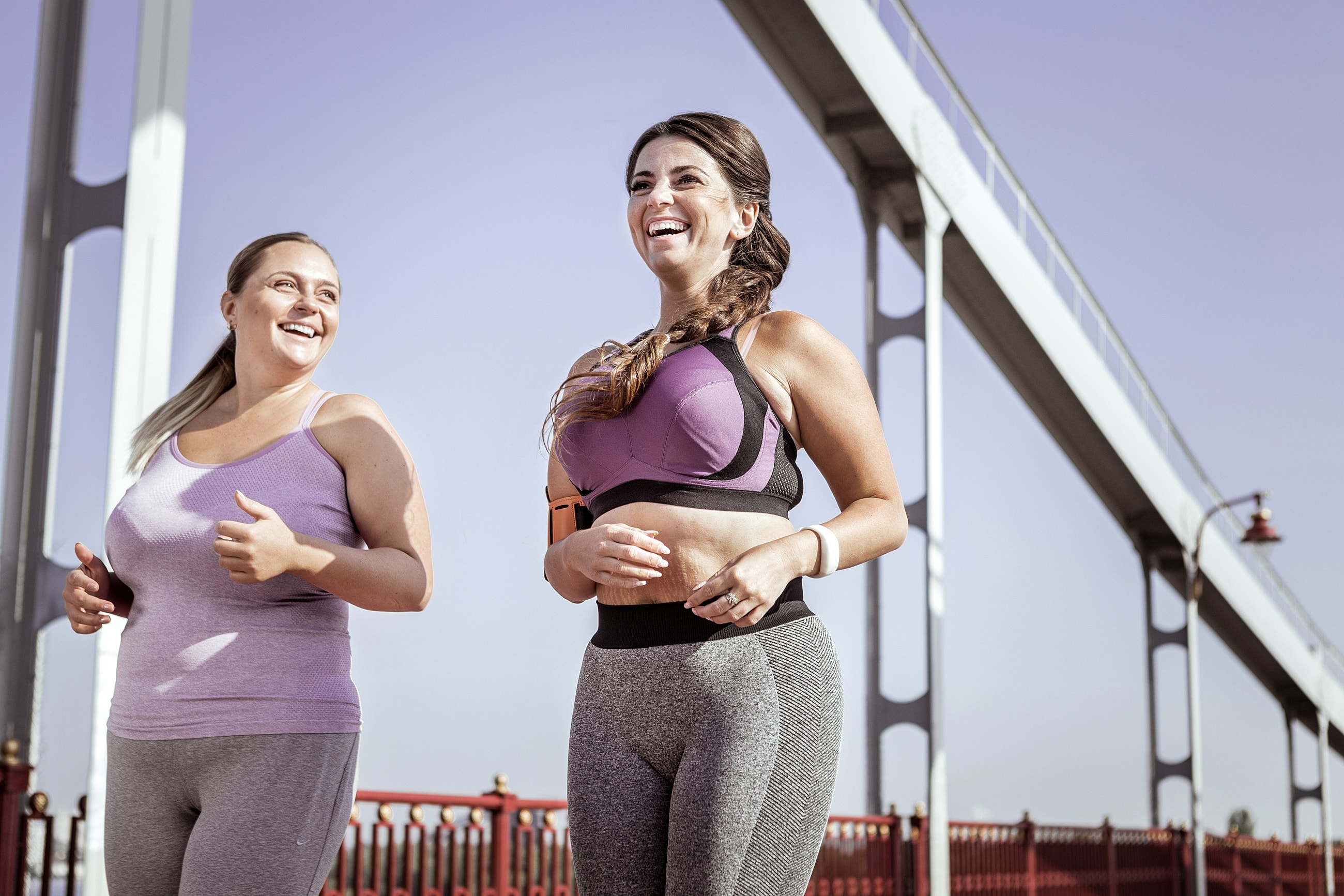 Two women jogging and smiling outdoors.