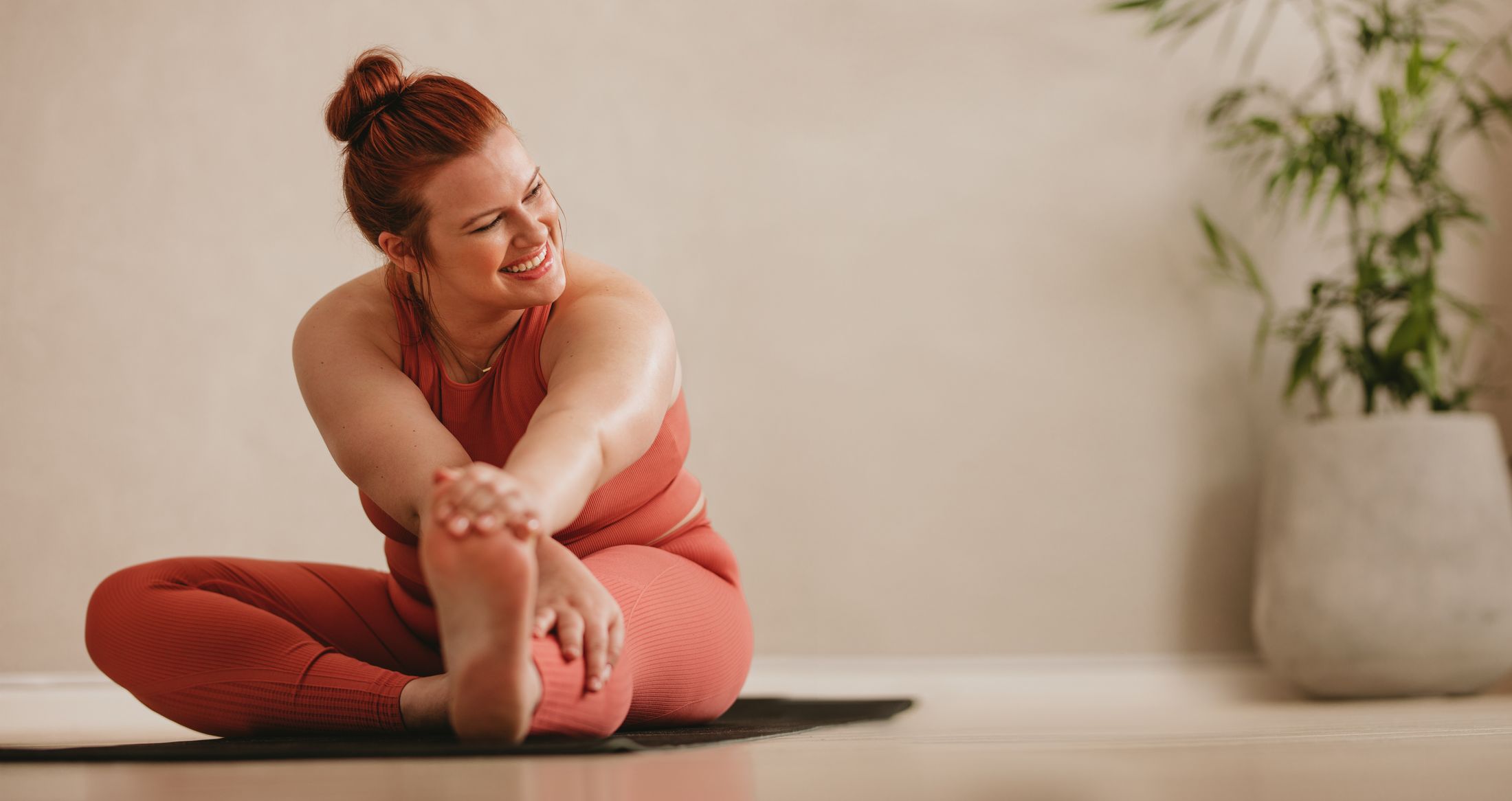 Woman stretching on a yoga mat indoors.